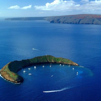 an island in the middle of a body of water with Molokini in the background